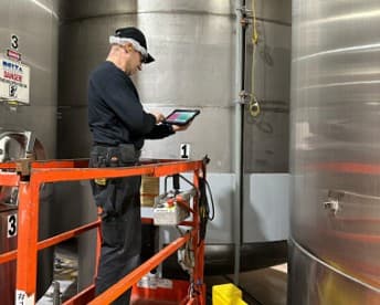A maintenance technician completing a work order on a mobile device at Delta Beverages.